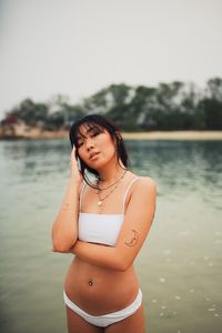 Portrait of sensuous young woman wearing bikini standing at beach