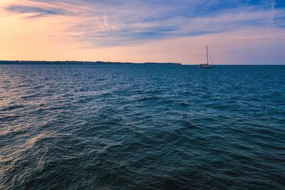 Sailboat sailing on sea against sky during sunset