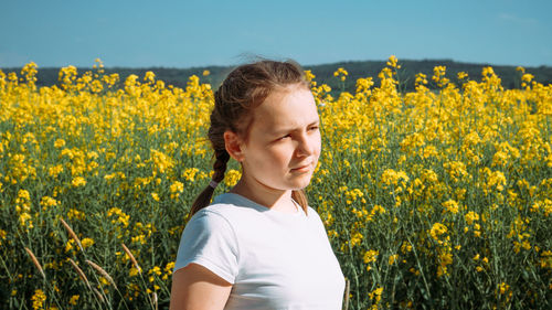 Scenic view of girl standing against oilseed rape field against sky