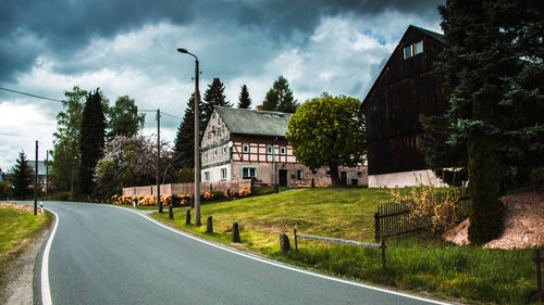 Road by buildings against sky