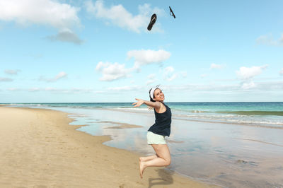 Portrait of happy woman jumping on beach