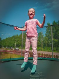 Full length of smiling girl standing against sky