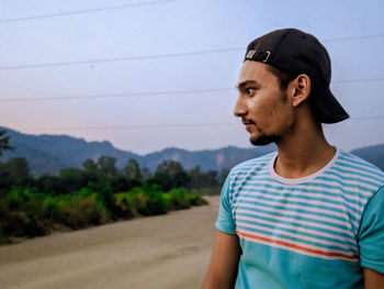 Portrait of young man looking away against sky