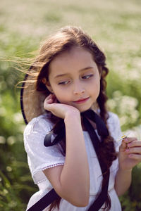 Portrait girl child in a white dress standing on a daisy field in a hat