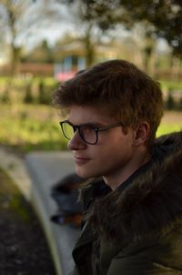 Close-up of boy looking away against trees