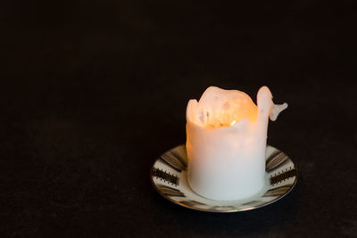 Close-up of lit candle on table against black background