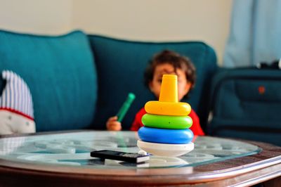 Boy with stacked colorful toys at table in home