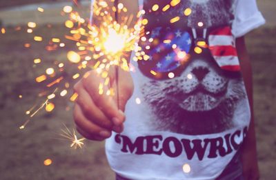 Close-up of boy holding sparkler while standing on field