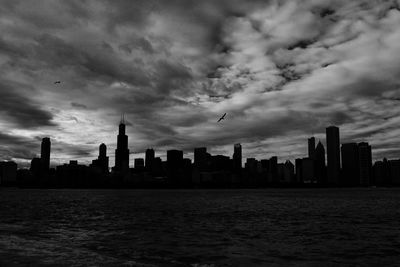 Sea by modern buildings against sky in city