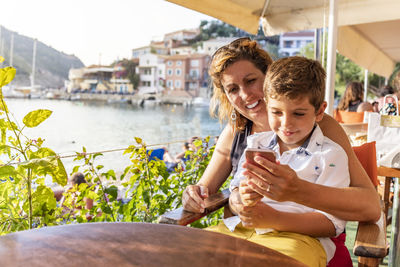 Smiling mother with son using smart phone while sitting in restaurant