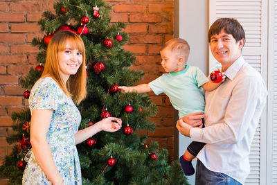 Full length of smiling young woman on christmas tree