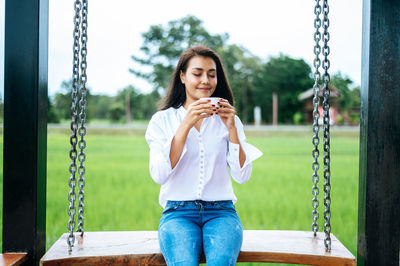 Full length of young woman sitting on swing
