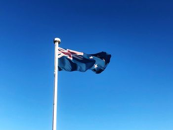 Low angle view of flag against clear blue sky