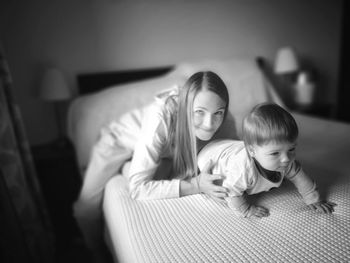 Mother and daughter while sitting on sofa at home