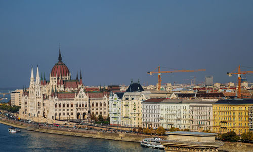 View of buildings by river against sky in city