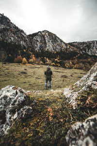 Rear view of man on rock against sky