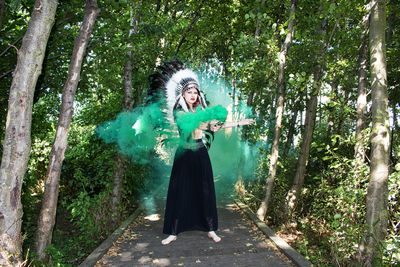 Woman standing by trees in forest