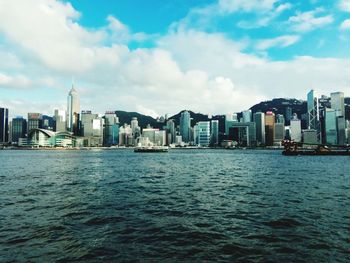 Sea by buildings against sky in city