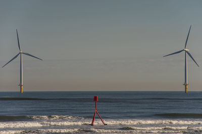 Wind turbines on sea shore against sky