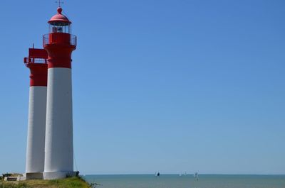 Lighthouses at seaside against clear blue sky