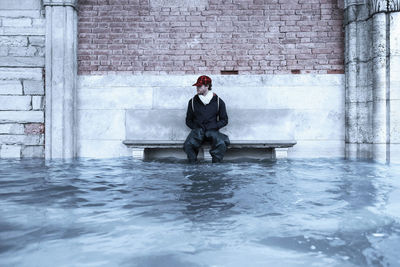 Portrait of young man sitting on wall