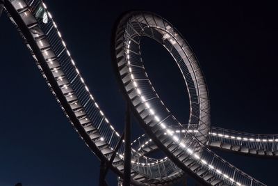 Low angle view of illuminated amusement park ride against sky at night