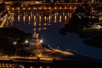 High angle view of illuminated buildings by river at night