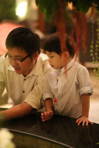 Father and son leaning on retaining wall