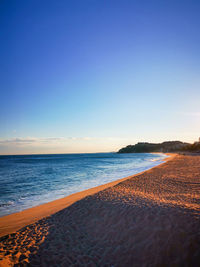 Scenic view of beach against clear sky during sunset