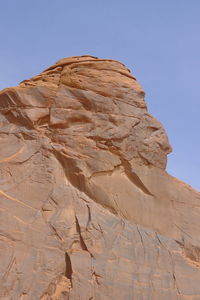 Low angle view of rock formations  looking like faces against blue sky