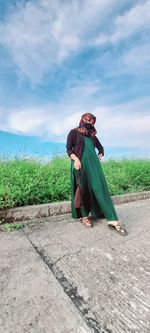 Side view of woman sitting on land against sky