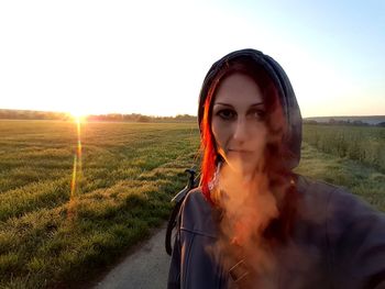 Portrait of woman standing on field against sky during sunset