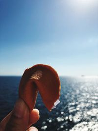 Cropped hand holding food against sea