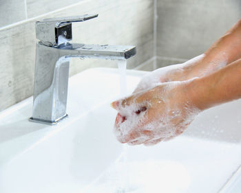 Close-up of hand touching water from faucet