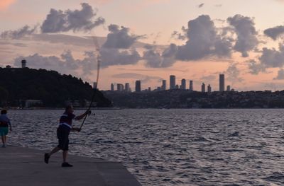 Full length of man by sea against sky during sunset