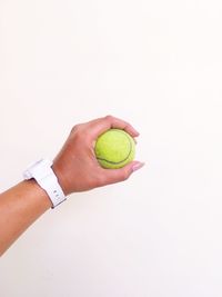 Midsection of person holding ball against white background