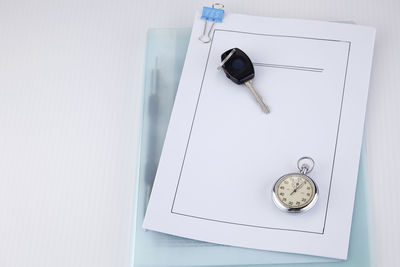 High angle view of car key and pocket watch on document