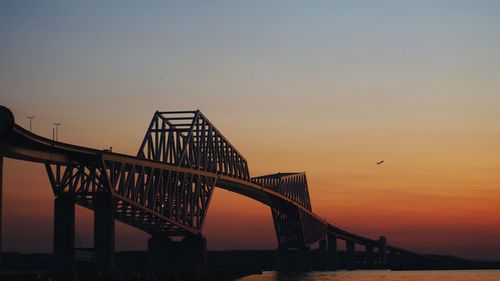 Bridge over river against clear sky during sunset