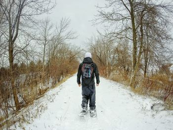 Rear view of man walking on snow covered footpath