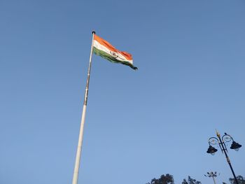 Low angle view of flags against clear blue sky