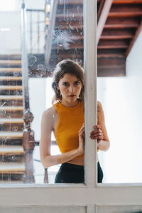 Portrait of woman standing against window