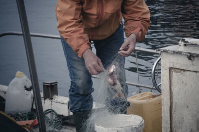 Midsection of man fishing at harbor