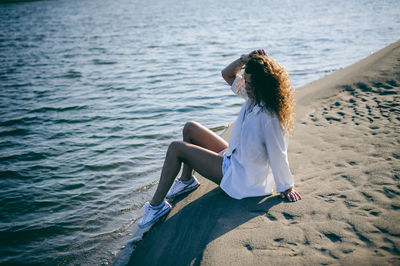 Young woman sitting on shore at beach