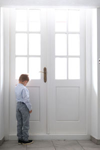 Boy standing against closed doors at home