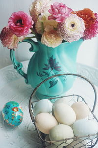 High angle view of eggs in basket by flower vase on table