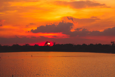 Scenic view of sea against dramatic sky during sunset