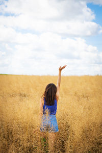 A girl in a blue t-shirt and denim shorts stands in the middle of a field