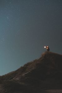 Low angle view of man on mountain against sky at night