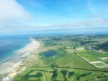 Aerial view of field and sea against blue sky