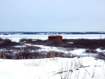 Scenic view of snow covered land by sea against sky